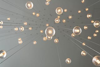 Photo of small light fixtures hanging from long wires as viewed from below.