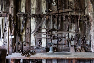 An image of rustic tools organised on a wall with a work bench underneath