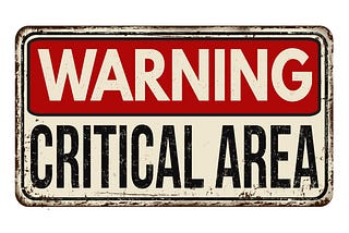 A white sign, with a red box inside that says Warning, and below it it says Critical Area