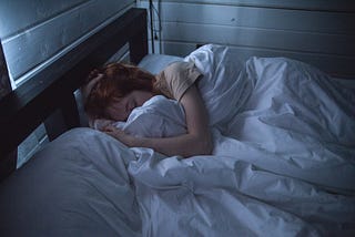 A redheaded female asleep in a dimly lit room.