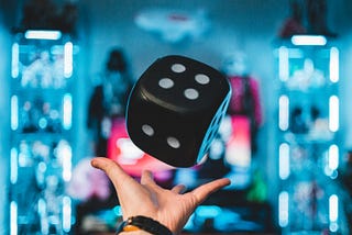 A hand throwing a large black dice.