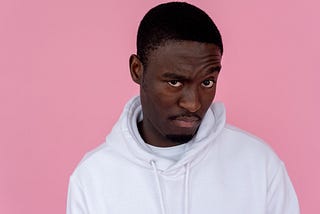 African American man in a white hoodie sweatshirt looking skeptical.