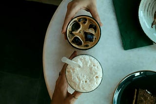 hands holding glasses of coffee