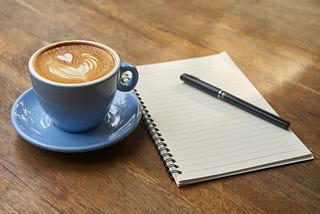 blue cup of coffee with a notepad on a table — ready to start your day