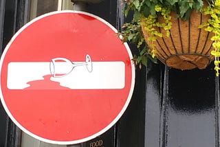 No Entry sign with an empty wine glass superimposed to look as if the red circle of the sign is spilled red wine.