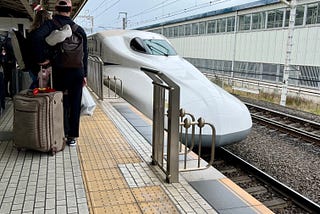 Shinkansen pulling into a station with minimal barriers.