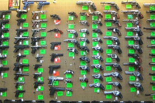 Multiple handguns with price tags on a wall.