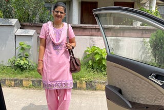 A woman looks at the passenger side of the car. The car door is open.