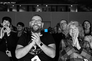 Black and white photo of Interaction 20 audience, seated, clapping and smiling.