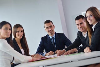 A manager with excellent persuasion skills sitting with his satisfied employees in the office.