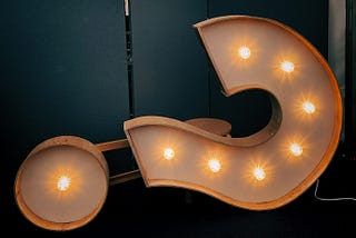 a large lighted question mark tilted on its right