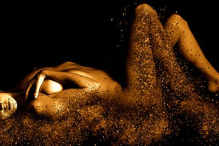 A naked woman adorned in golden light as she is shattered into shards by desire.