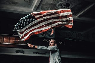A man waving the US flag in an abandoned room