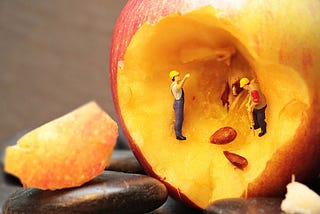 Tiny Like Lego Tradesmen Figures Working Inside The Core Of An Apple.