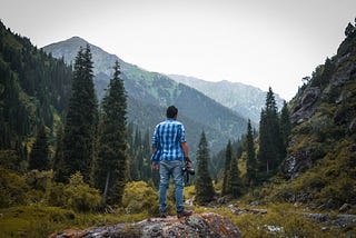 Man with a camera standing outside a beautiful forest