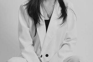 torso of a person with long hair wearing a white blazer