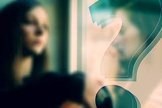 Woman in blurred image looking at a large blue question mark