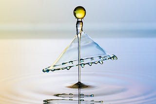 Colorful droplet rising from pool of water
