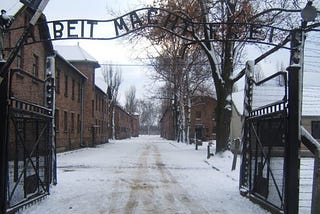 Image of the entrance to the Auschwitz Concentration Camp, snow blankets the ground