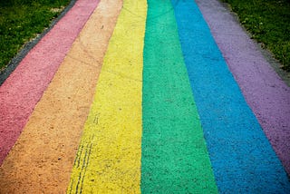 A sidewalk filled with rainbow stripes in chalk.