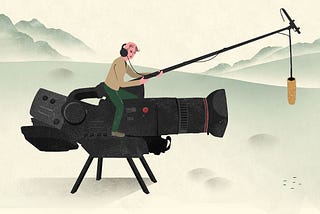 Producer sitting on a gigantic video camera to film