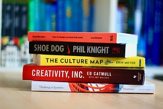 Stack of 5 recommended design books: Thinking in Systems, Creativity Inc, The Culture Map, Shoe Dog and Good Services