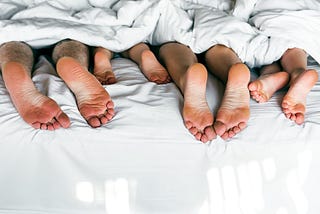 Picture with a blanket over a family while her foot sticks out.