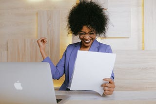 woman celebrating success while looking at a sheet of paper