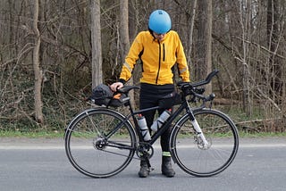 A cyclists bows his head in prayer on a forest road