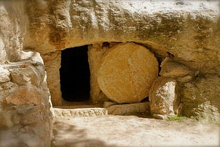 In this representation of the empty tomb of Jesus, a round stone is rolled away from an open door of what appears to be a tomb hewed out of stone.