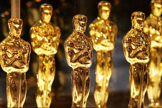 Six solid gold statuettes of men standing upright. These are Oscar statuettes.