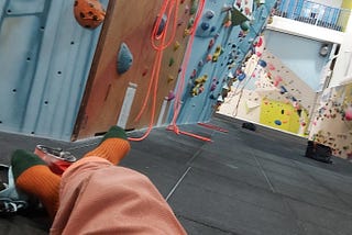 The author Trisha Lewis contemplating a difficult climb at indoor climbing wall.