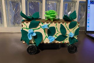 Box with a green flower and felt leaves on wheels