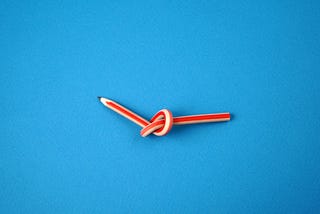 A pencil tied in a knot on a blue background