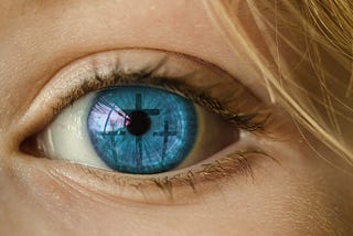 A close-up  shot of a beautiful blue eye reflecting three crosses across the iris