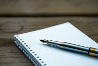 A pen and a notebook on a wooden table