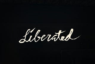 Cursive text — Liberated — on a black background