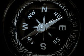 Close up view of a compass face with North at the top and the dial pointing to the South West Direction