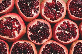 Lines of fresh pomegranates sliced in half with arils facing up