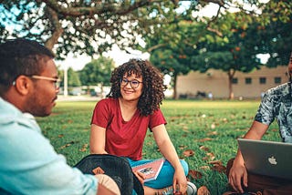 Man chatting to two friends in a university campus.