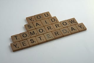 Brown wooden blocks on white table creating the phrase “you said tomorrow yesterday”