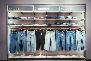 A rack of jeans in a store, with signs above that say “Skinny,” “Jeggings,” and “Skinny” again.