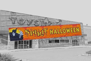 An old Toy R Us store in black and white with an orange Spirit Halloween banner over it.