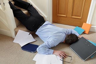 Businessman lying on floor at home surrounded by papers