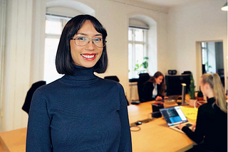 Woman with glasses and short hair smiling in front of the camera.