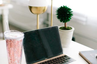 Laptop on desk with rose gold cup and gold desk ornaments