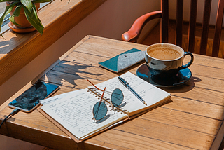 a writing table with a journal and a pair of sunglasses sitting on top