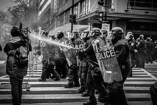 Grayscale photo of police riot team on pedestrian lane. Original public domain image from Wikimedia Commons