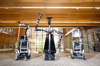 Three artificial intelligence robots stand in a building at The University of Texas at Austin.