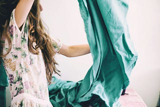 A woman with long hair hold up a large piece of green fabric